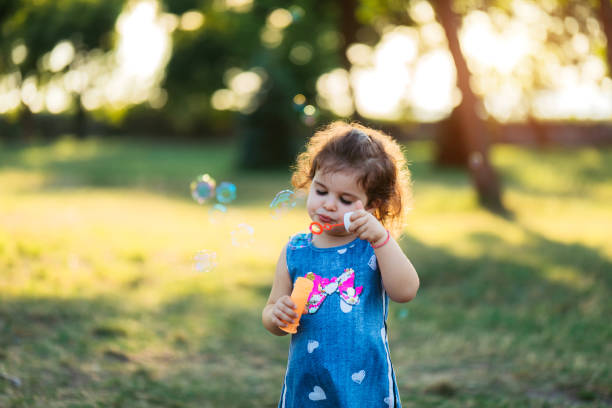 istock Little girl blowing soap bubbles 1174111072