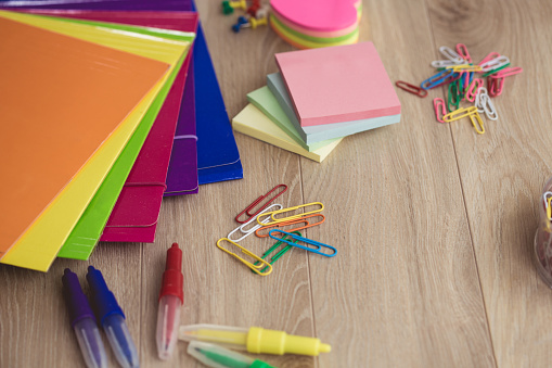 Colorful folders, paper clips, sticky notes and felt pens on work desk.