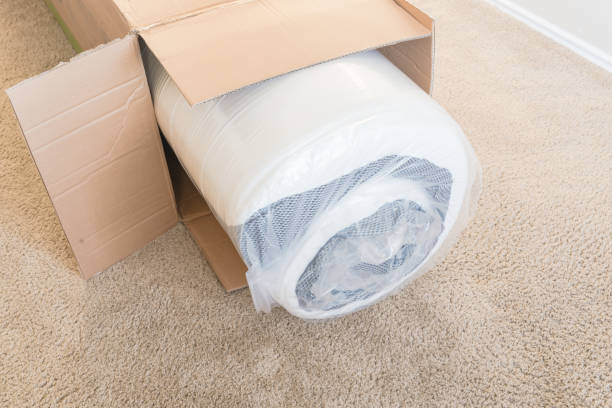 Close-up top view roll-packed spring mattresses unbox on carpet floor background stock photo