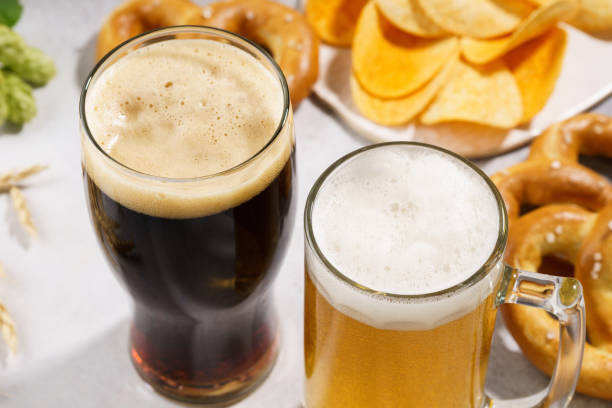 istock Two glasses of beer - light and dark with various snacks. 1174113958
