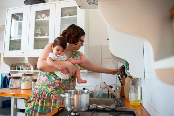 istock Mother holding her baby and preparing lunch 1174114191