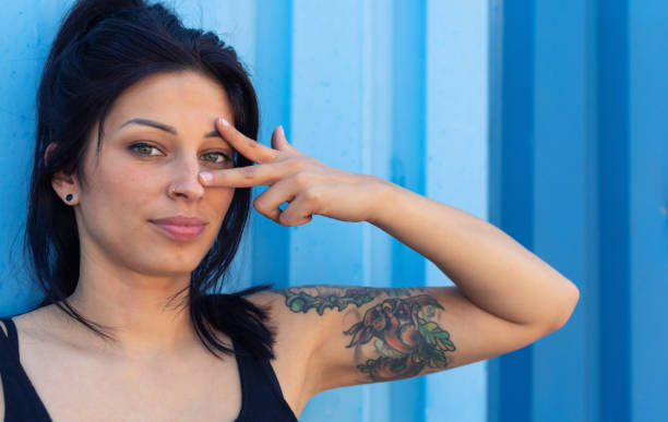 istock Young tattooed woman looking through fingers 1174118595