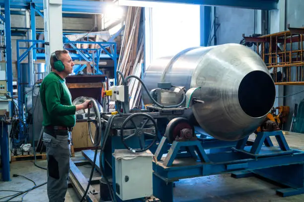 Industry worker polishing stainless steel tank in workshop