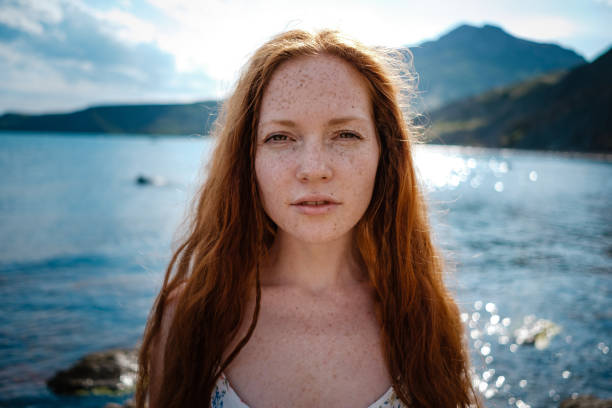istock Beautiful boho styled model wearing white dress posing on the beach in sunlight 1174129499