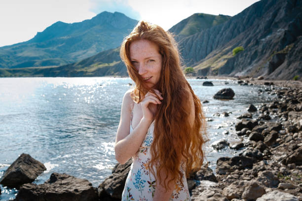 istock Beautiful boho styled model wearing white dress posing on the beach in sunlight 1174129624
