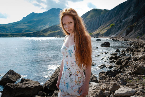 istock Beautiful boho styled model wearing white dress posing on the beach in sunlight 1174129715
