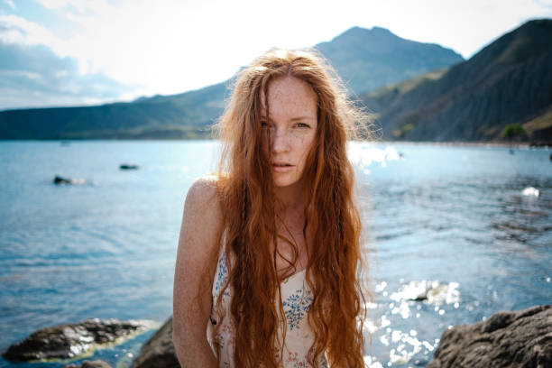 Beautiful boho styled model wearing white dress posing on the beach in sunlight