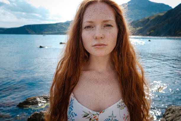 istock Beautiful boho styled model wearing white dress posing on the beach in sunlight 1174129858