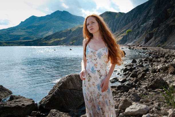 istock Beautiful boho styled model wearing white dress posing on the beach in sunlight 1174130000
