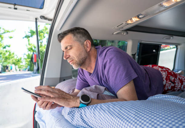 homme aîné avec le smartphone dans le campeur - motor home mobile home camping senior adult photos et images de collection