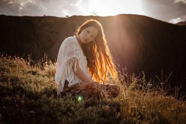 istock Red-haired cute woman resting in sunset mountains. 1174131574