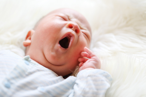 Yawning and sleeping newborn baby on the bed
