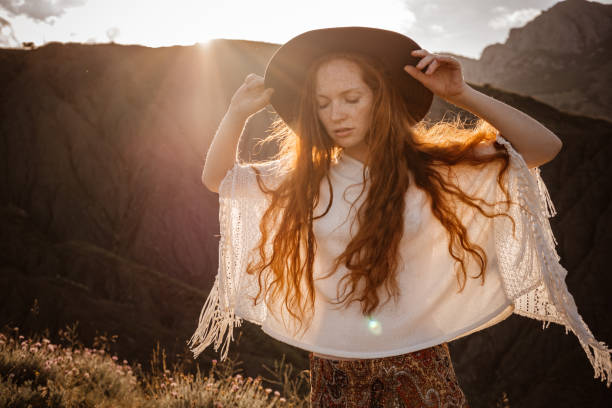 istock Red-haired cute woman resting in sunset mountains. 1174132225