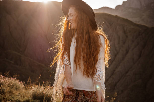 istock Red-haired cute woman resting in sunset mountains. 1174133220