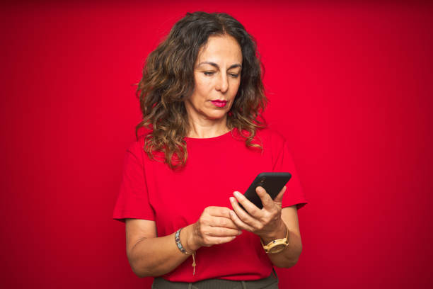 istock Middle age senior woman using smartphone over red isolated background with a confident expression on smart face thinking serious 1174133347