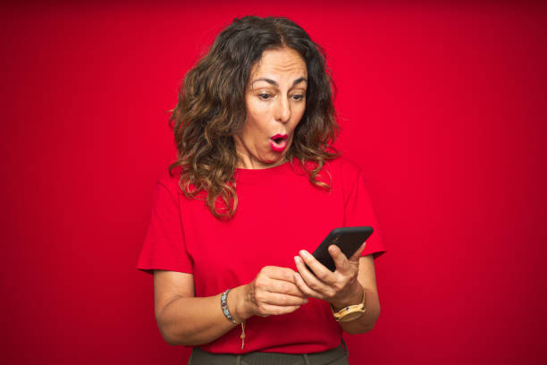 istock Middle age senior woman using smartphone over red isolated background scared in shock with a surprise face, afraid and excited with fear expression 1174133348