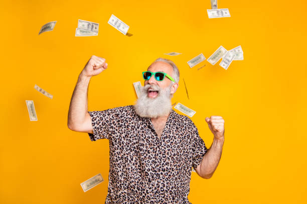 Portrait of crazy retired funky bearded old man with eyeglasses eyewear raise his fists scream yeah celebrate victory look at money falling wearing leopard shirt isolated over yellow background Portrait of crazy retired funky bearded old man with eyeglasses eyewear raise his fists, scream yeah celebrate victory look at money falling wearing leopard shirt isolated over yellow background jackpot winner stock pictures, royalty-free photos & images