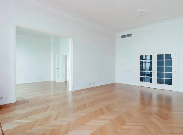 Photo of Empty white room with washed floating laminate flooring and newly painted wall in background