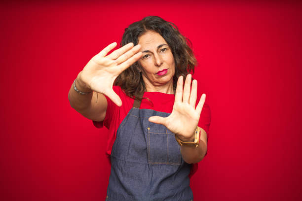 istock Middle age senior woman wearing apron uniform over red isolated background doing frame using hands palms and fingers, camera perspective 1174138042