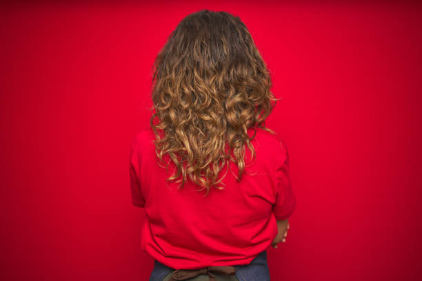 Middle age senior woman wearing apron uniform over red isolated background standing backwards looking away with crossed arms