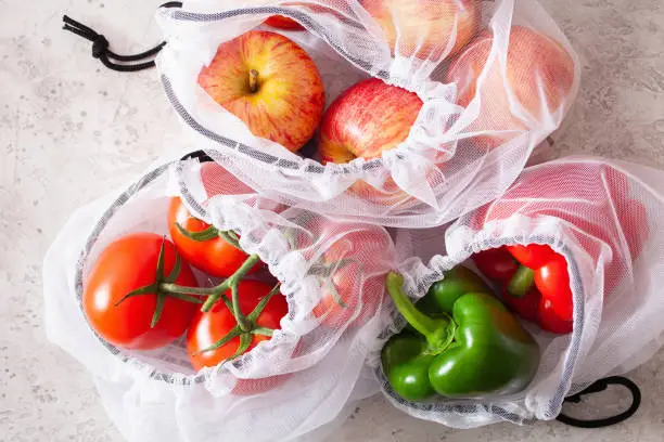 apples tomatoes bell peppers vegetables in reusable mesh nylon bag, plastic free zero waste concept