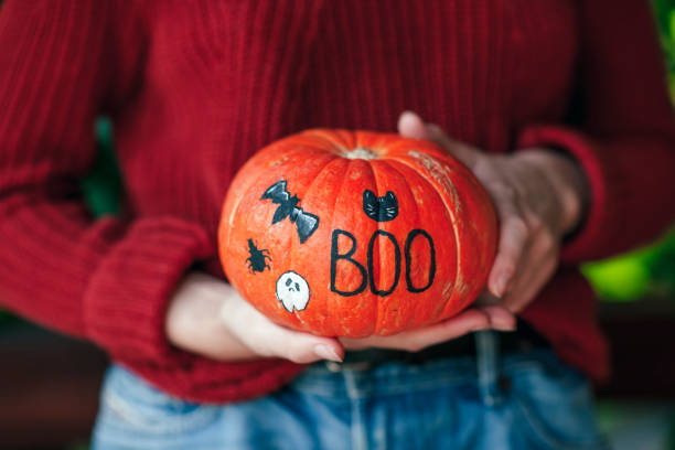 frau hält den jack o'lantern kürbis an halloween - miniature pumpkin stock-fotos und bilder