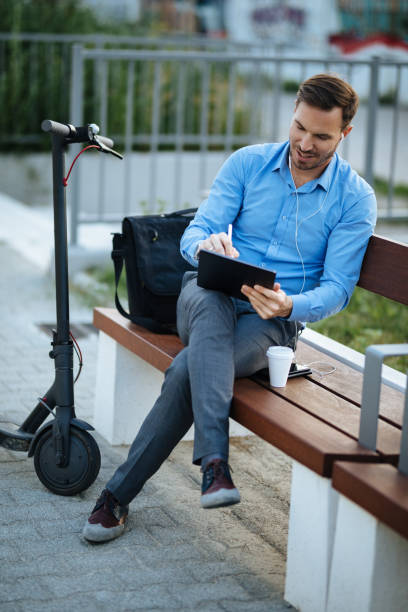 istock Businessman using digital tablet in the city park after scooter riding 1174144324