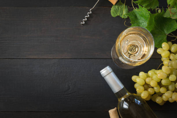 bottle of white wine with wineglass, ripe grape on black wooden table. - wine glass white wine wineglass imagens e fotografias de stock
