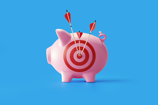 Piggy bank with bulls eye target and  red arrows standing on blue background. Horizontal composition with copy space. Great use for financial concepts.
