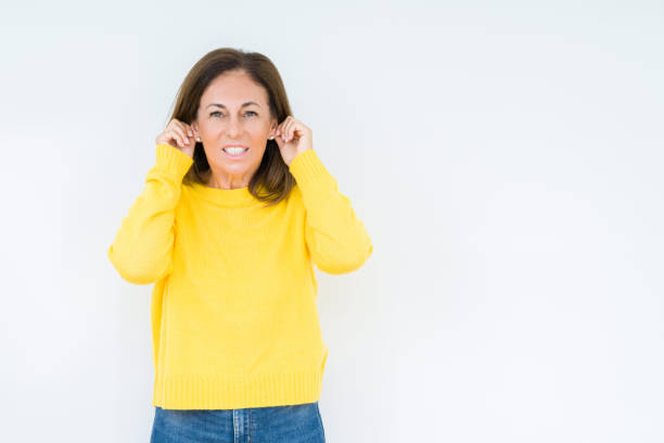 istock Beautiful middle age woman wearing yellow sweater over isolated background Smiling pulling ears with fingers, funny gesture. Audition problem 1174155486