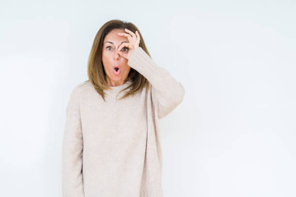 istock Beautiful middle age woman over isolated background doing ok gesture shocked with surprised face, eye looking through fingers. Unbelieving expression. 1174155706