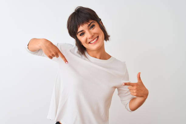 mulher bonita nova que desgasta o t-shirt ocasional que está sobre o fundo branco isolado que olha confiável com sorriso na face, apontando oneself com os dedos orgulhosos e felizes. - white women - fotografias e filmes do acervo