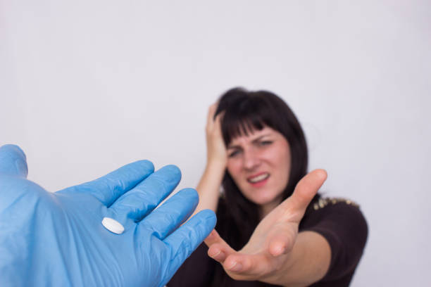 der arzt hält eine kopfschmerz-pille für ein mädchen, das kopfschmerzen hat, das konzept der antispasmodicen und analgetika für kopfschmerzen - ibuprofen stock-fotos und bilder