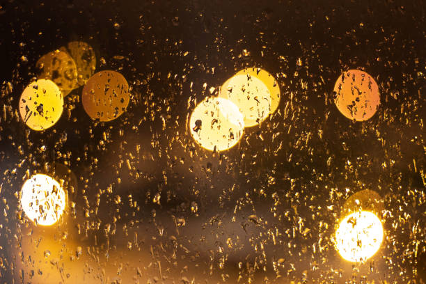 istock Wet glass with drops and light from lamps, background, night 1174166630