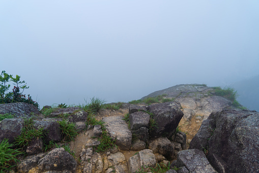 Stones on mountain or hill at the cliff peak of Lion Rock, Hong Kong in the morning with winter fog and copy space. Natural landscape background. White sky.