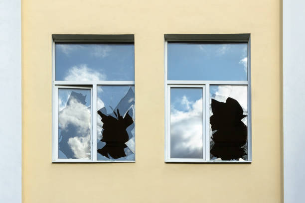 das glas zerbrochener fenster reflektiert den himmel, ein haus mit zerbrochenen fenstern aus der nähe. - smashed window stock-fotos und bilder