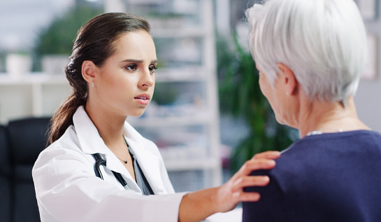 Cropped shot of a young female doctor consoling an elderly patient inside of her office