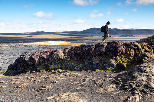 Photographer walking along lava