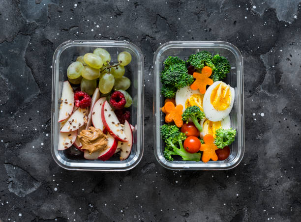 istock Healthy diet snack, breakfast lunch box on dark background, top view. Boiled egg, fresh vegetables and fruits - tasty healthy food concept 1174207887