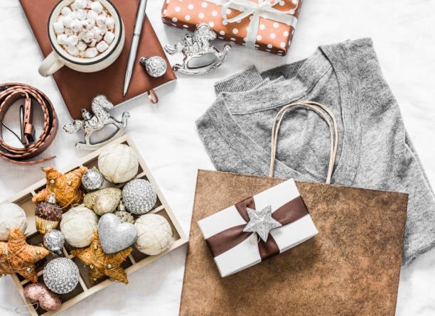 istock Christmas mood background. Festive Christmas shopping concept. Grey cashmere pullover, gift box, notepad, christmas decorations, hot chocolate with marshmallow on white background, top view. Flat lay 1174207962
