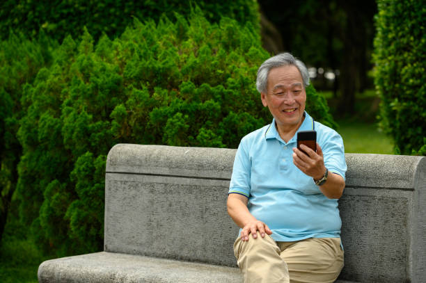 istock Smiling senior man using smart phone at park bench 1174219563
