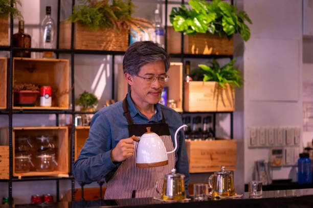 istock Confident mature barista holding kettle at cafe 1174219628