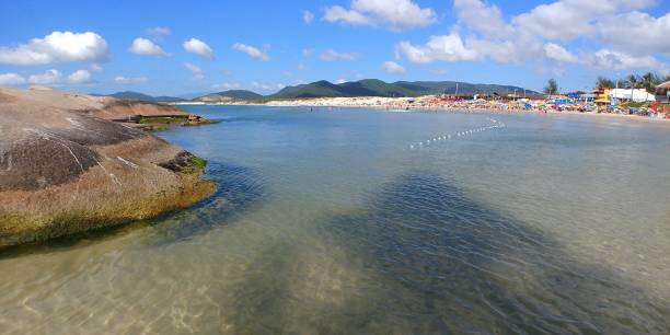 Joaquina beach coastline, the Atlantic Ocean, mountains and rocky formations in Florianopolis, Brazil. Rocks, the Atlantic Ocean and Joaquina beach seen from one end of the beach. joaquina beach in florianopolis santa catarina brazil stock pictures, royalty-free photos & images