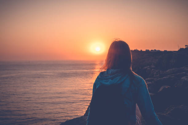 Girl watching the sunset on the ocean, beautiful ocean coast