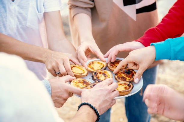 Group of people take pashtel de nata traditional Portuguese dessert with plate Group of people take pashtel de nata traditional Portuguese dessert with plate pasteis de belem stock pictures, royalty-free photos & images
