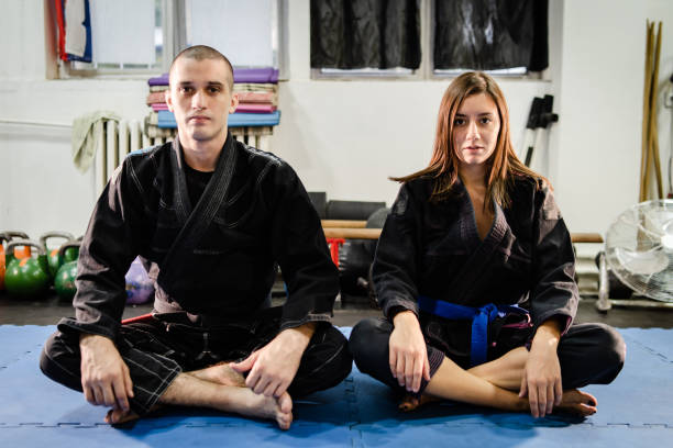 brasilianische jiu jitsu bjj paar jiujitsu in schwarz kimono gi mann und frau weibliche mädchen sitzt auf den tatami-matten in der akademie auf training - ju jitsu stock-fotos und bilder