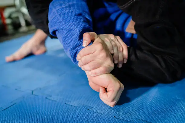 Brazilian Jiu jitsu BJJ jiujitsu training sparring athlete fighter applying kimura or americana shoulder lock submission on his opponent during technique practice