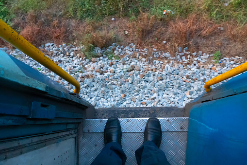 A pair of shoes of a passenger on the front gate of a railway coach while the train is passing through railway tracks. Huge passengers are carried across the country by coaches and helps travellers.