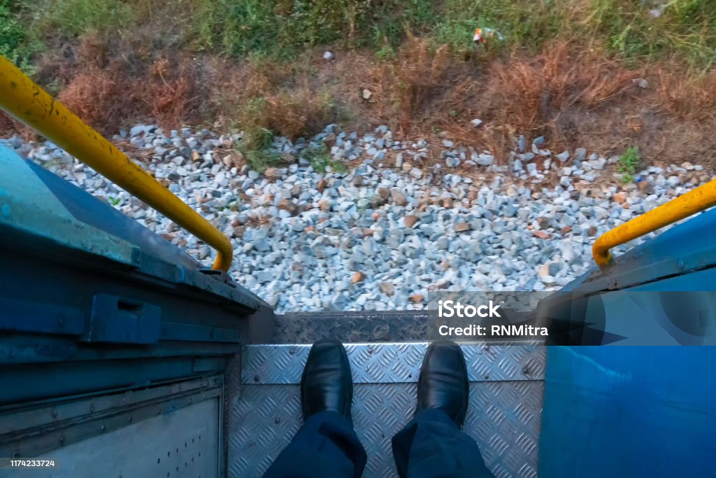 Train passenger, Indian railway A pair of shoes of a passenger on the front gate of a railway coach while the train is passing through railway tracks. Huge passengers are carried across the country by coaches and helps travellers. Carriage Stock Photo