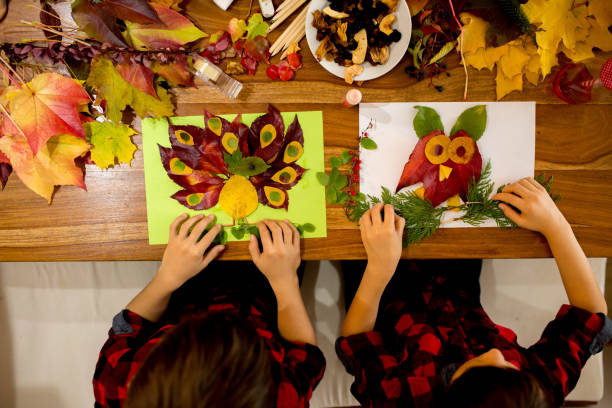 istock Children, applying leaves using glue, scissors, and paint, while doing arts and crafts in school 1174236687